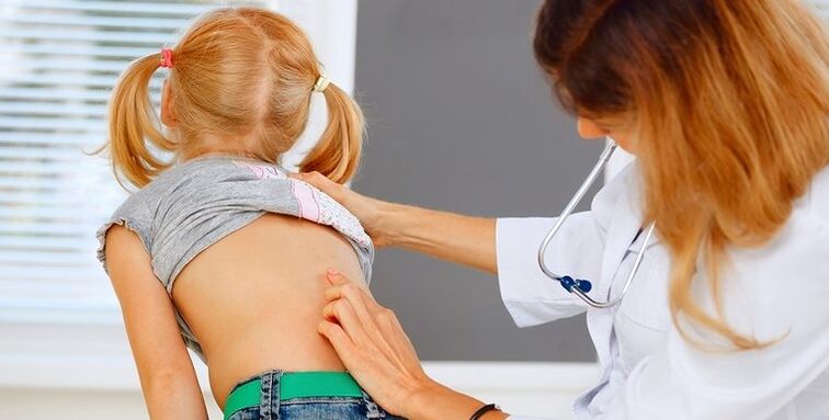 doctor examining the back of a child with low back pain